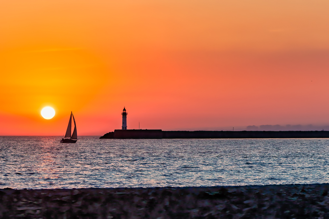 stock photo of sailboat sunset and lighthouse