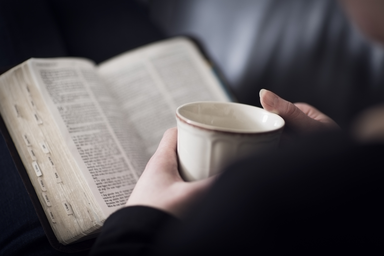 woman reading Bible with cup of tea