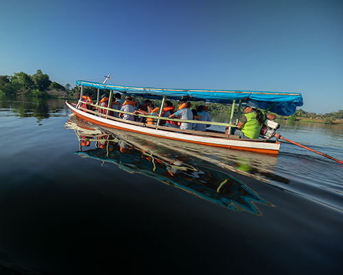 The ETAM “driver” uses a motorized covered boat to transport students to school. 