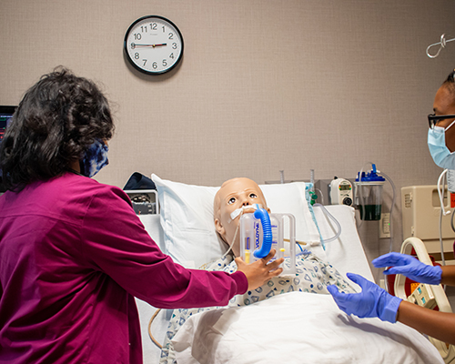 Two nurses caring for a medical simulation manikin