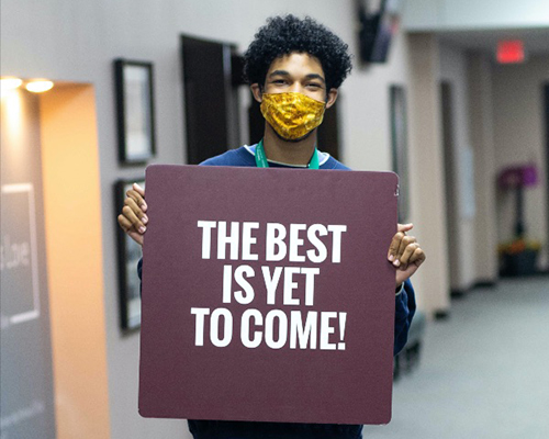 Man holding sign "The Best is Yet to Come!"