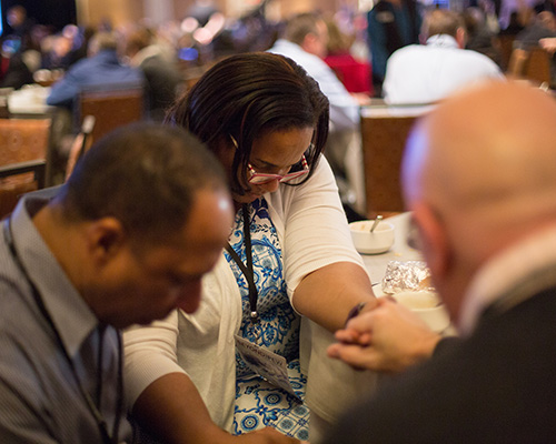 three people of different ethnicities praying together