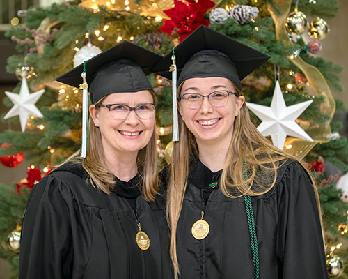 Two women in graduation hats smiling towards the camera.