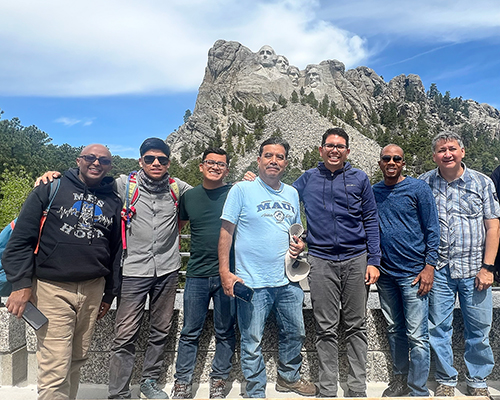 Diverse group of men standing in front of Mount Rushmore