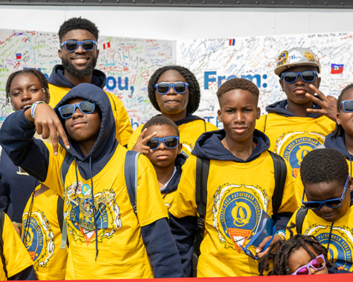 A group of young people in yellow Patfhinder t-shirts stand in front of big thank-you card