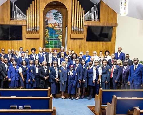 A group stands at the front of a church, most wearing matching blue uniforms