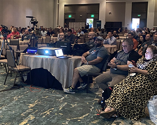 Group of people in a hotel ballroom listening to a religious presentation