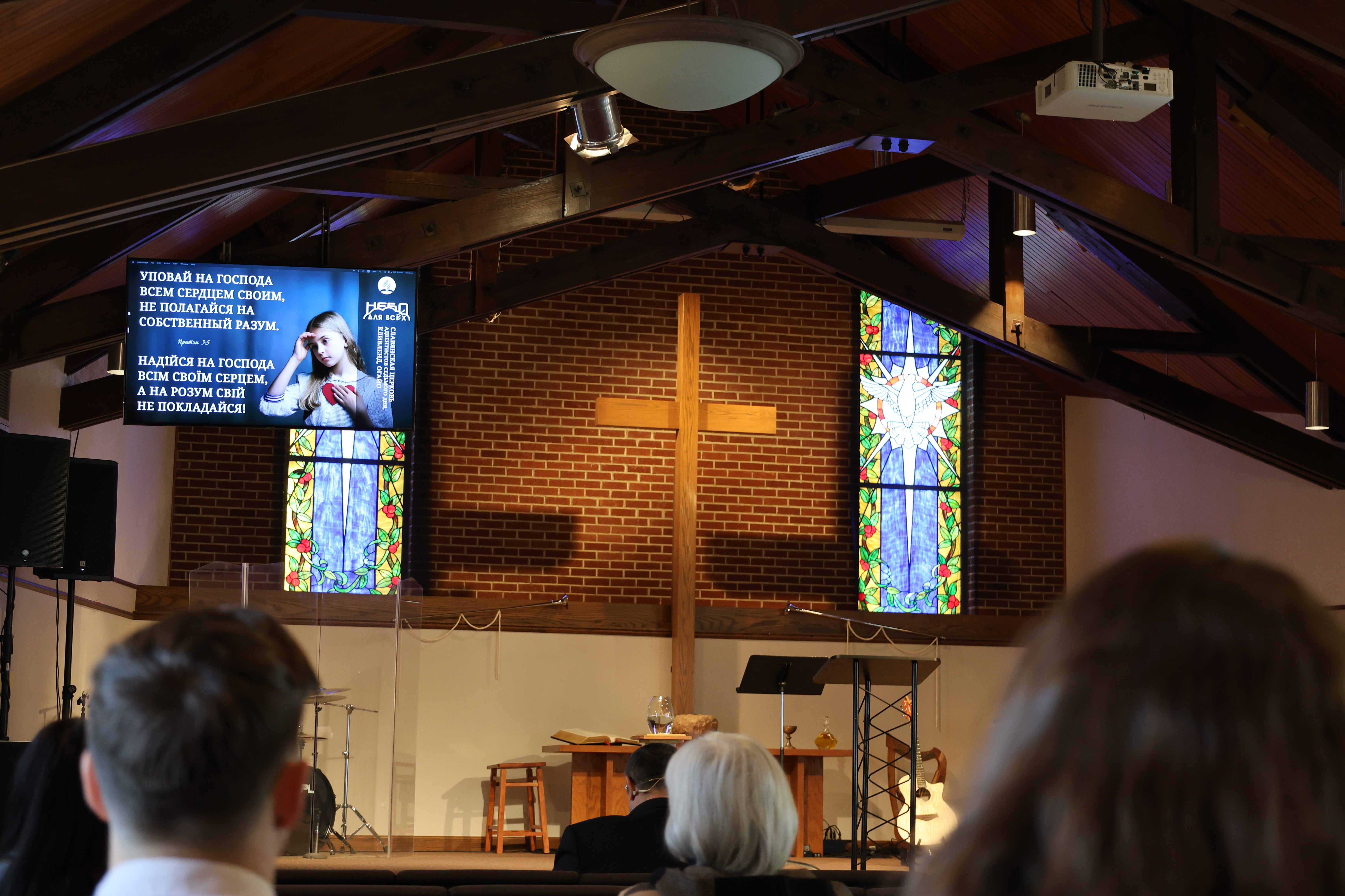 People look at a screen with Russian and Ukranian text in a sanctuary. 