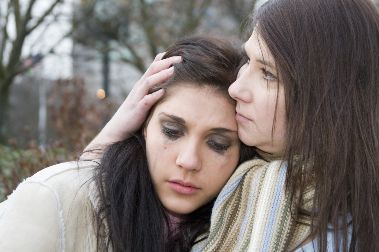 mother comforts crying teen daughter