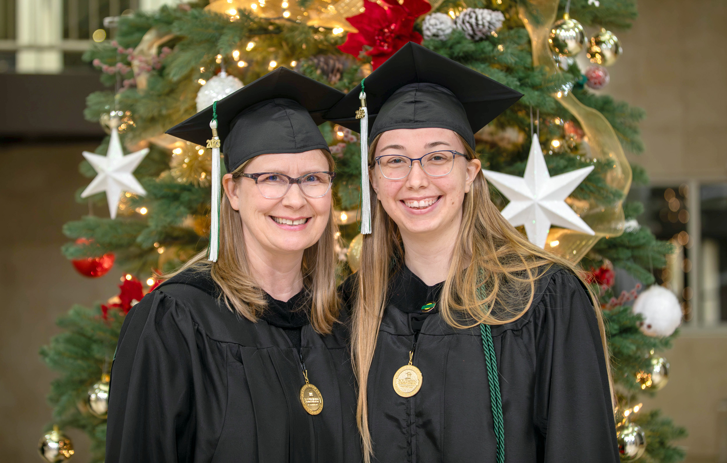 Two women in graduation caps smiling and looking towards the camera.