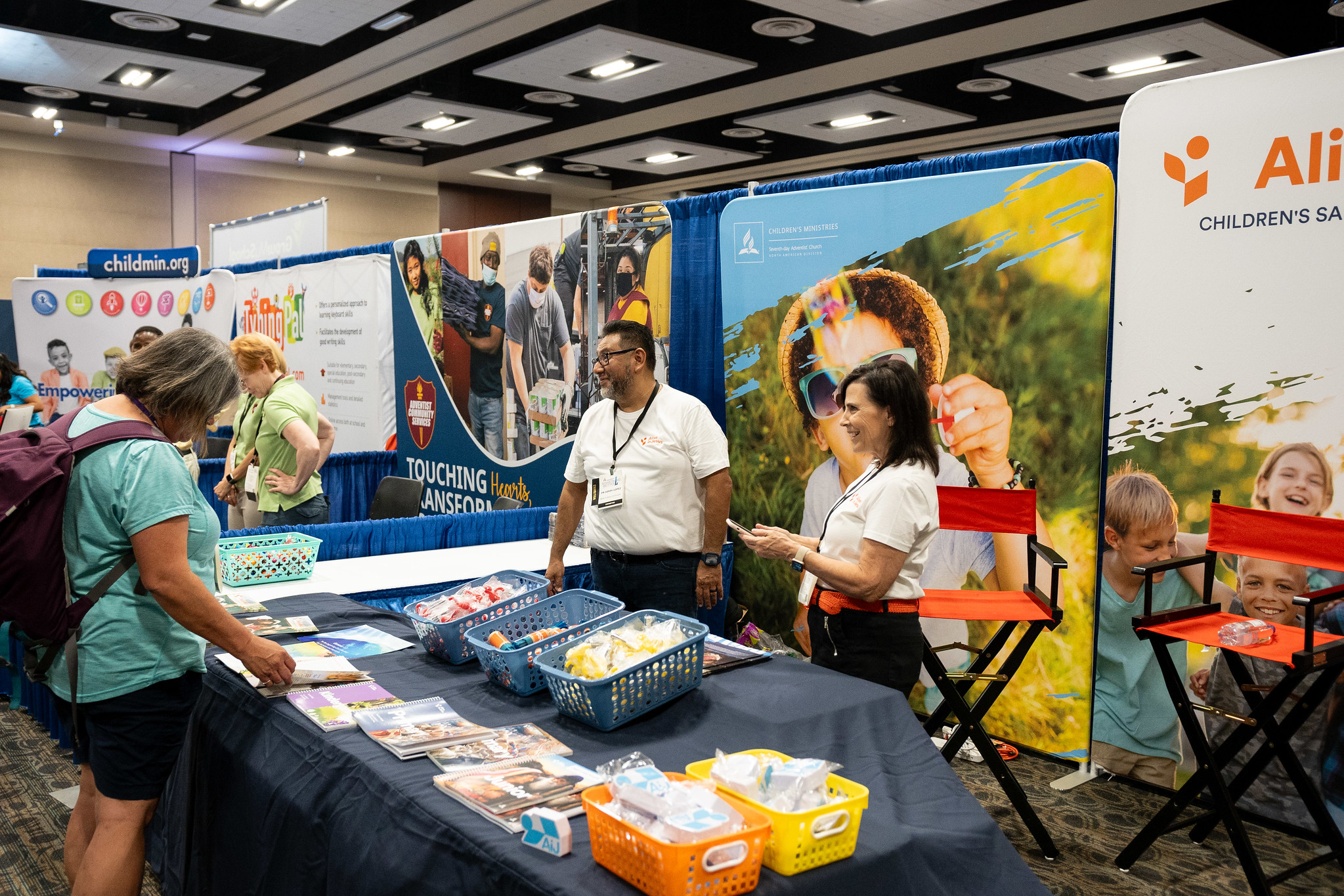 Children's Ministries leaders, Sherri Uhrig, director, and Gerry Lopez, associate director, hand out gifts and answer questions about the new Sabbath School curriculum launching soon. 
