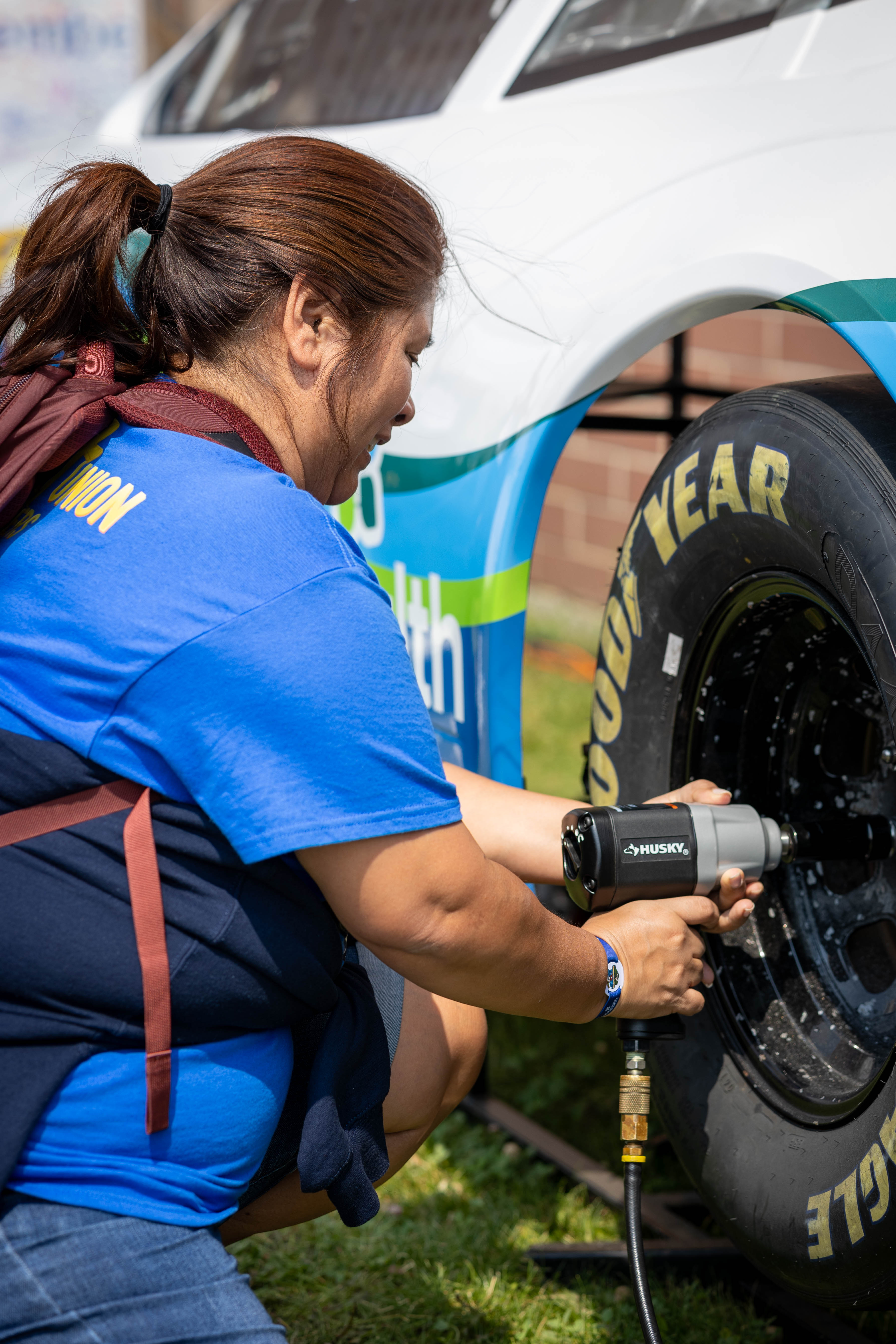 A woman changing a tire on a NASCAR vehicle