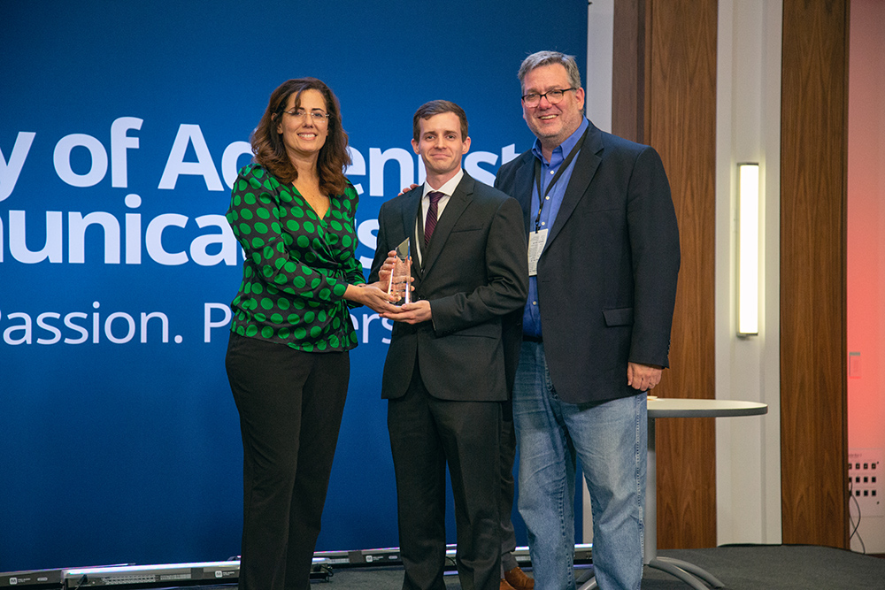 Shane Hochstetler (center) accepts the “Cutting Edge Award” for his work on the Gulf States Camp Meeting Campaign, “Forgiven to Forgive.” The award is presented by Libna Stevens, president of SAC, and Daniel Weber, executive director of SAC.  