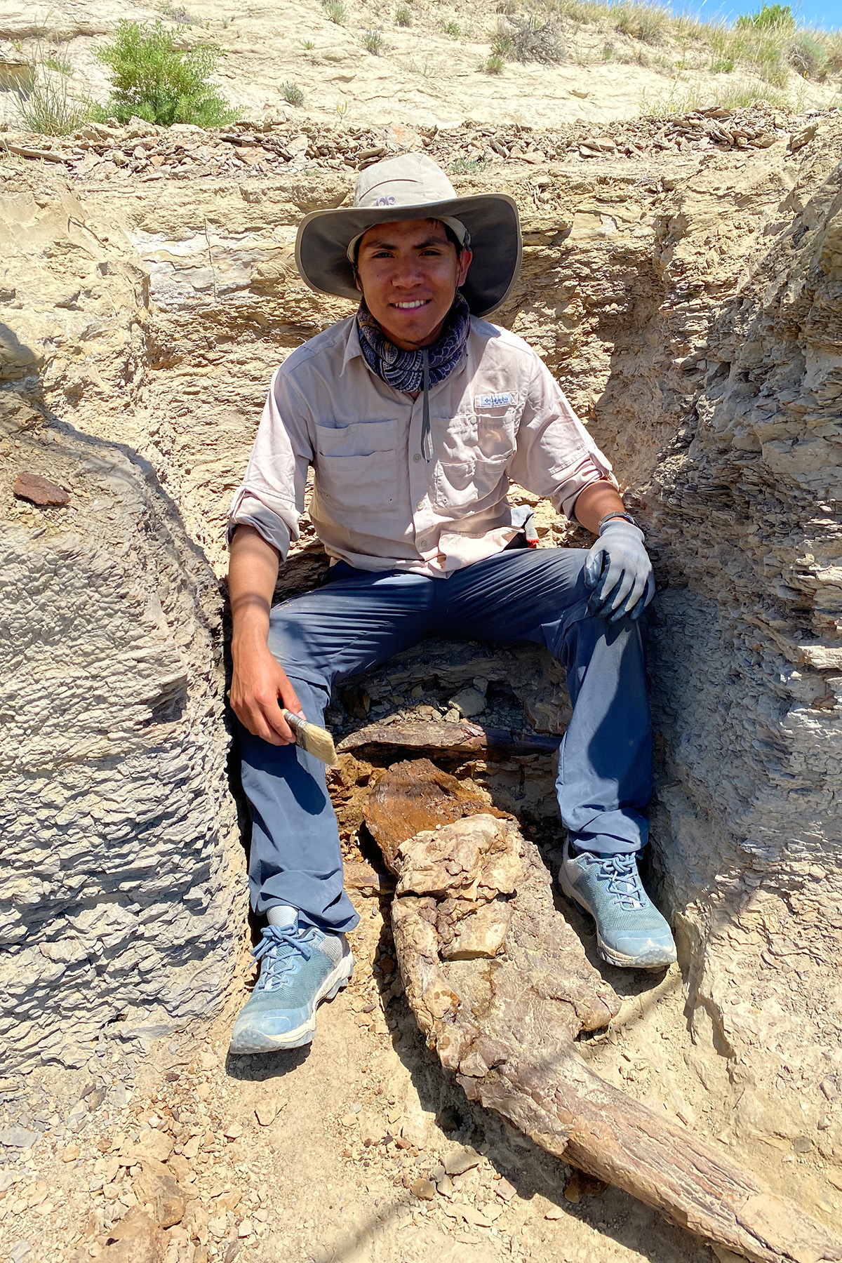 a casually dressed smiling Hispanic man sitting among rocks 