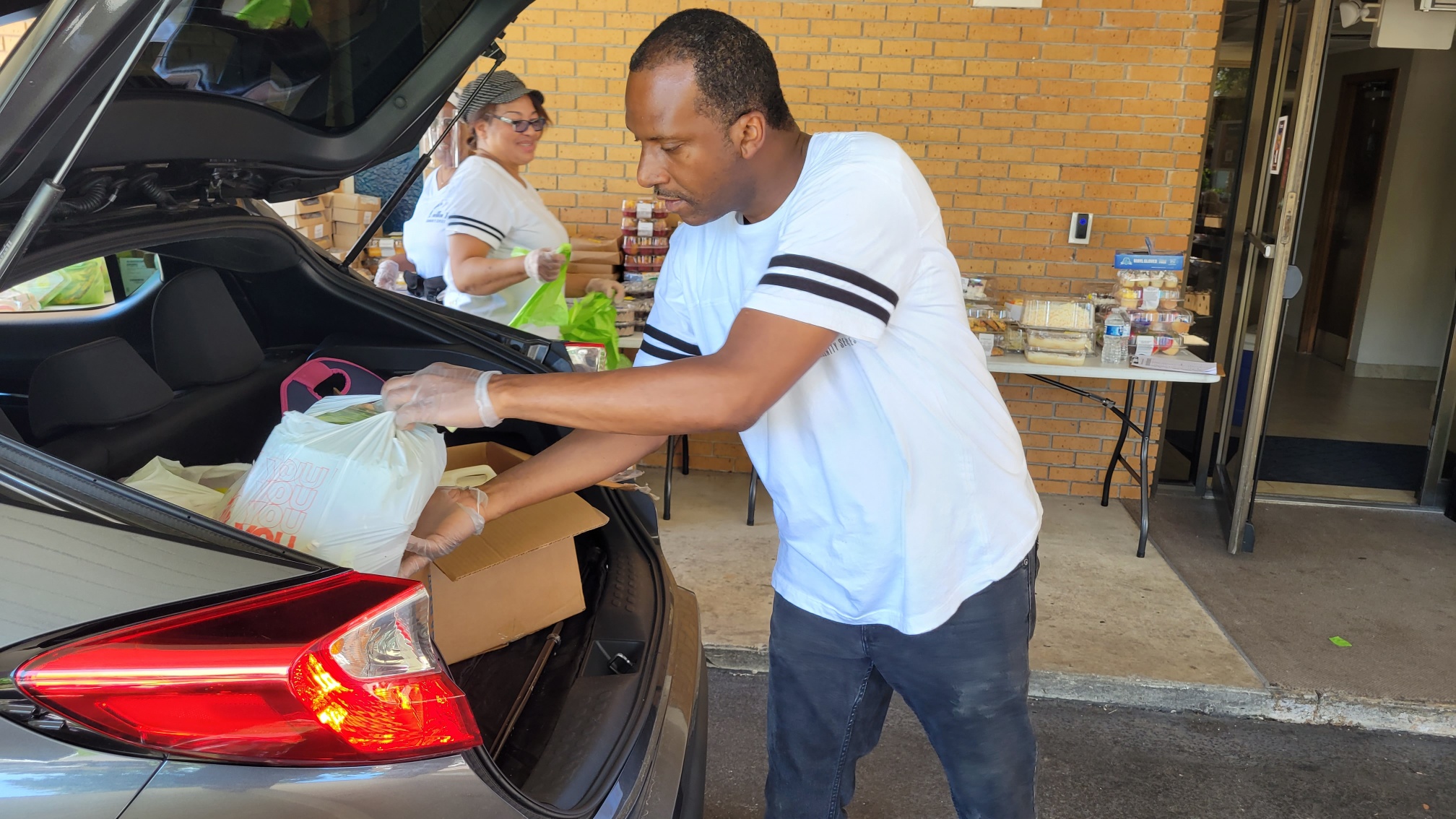 Black man loads groceries into a car