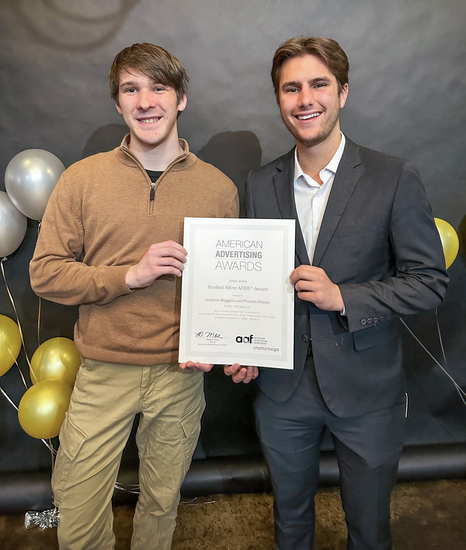 Two young men holding an award and smiling.