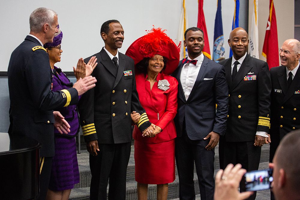 Washington Johnson, II poses with family and colleagues after receiving his new service dress coat, which reflects his new ranking