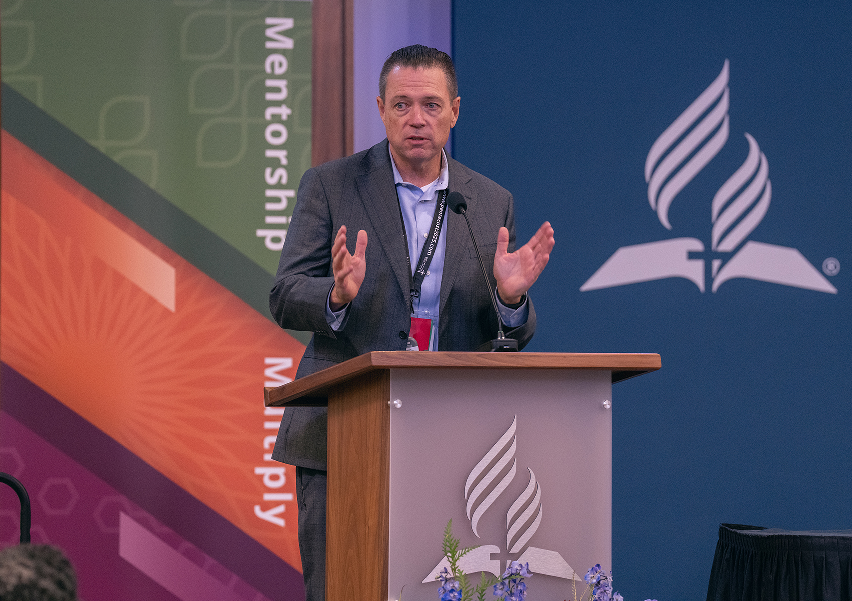 A white man speaks emphatically behind a podium in the North American Division auditorium.