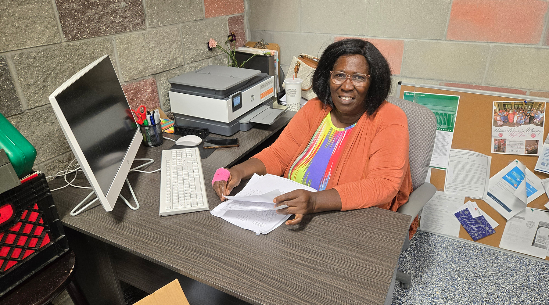 A smiling black woman sits at a desk