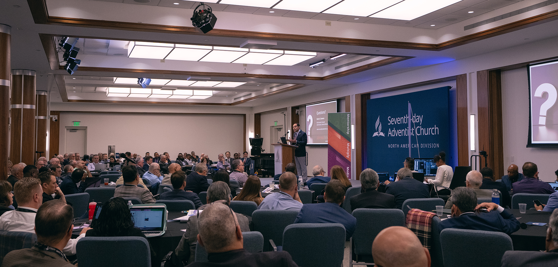 Wide angle shot of a man speaking in front of a crowd