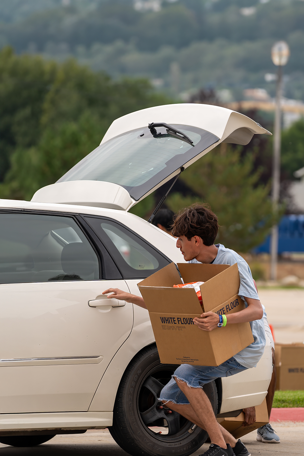 One of the 45 community service activities Pathfinders assisted with during the 2024 “Believe the Promise” International Pathfinder Camporee was a drive-through food distribution initiative run by the Church of Jesus Christ of Latter-day Saints. Photo: Charles Aguilar [photo of the young man loading a car]