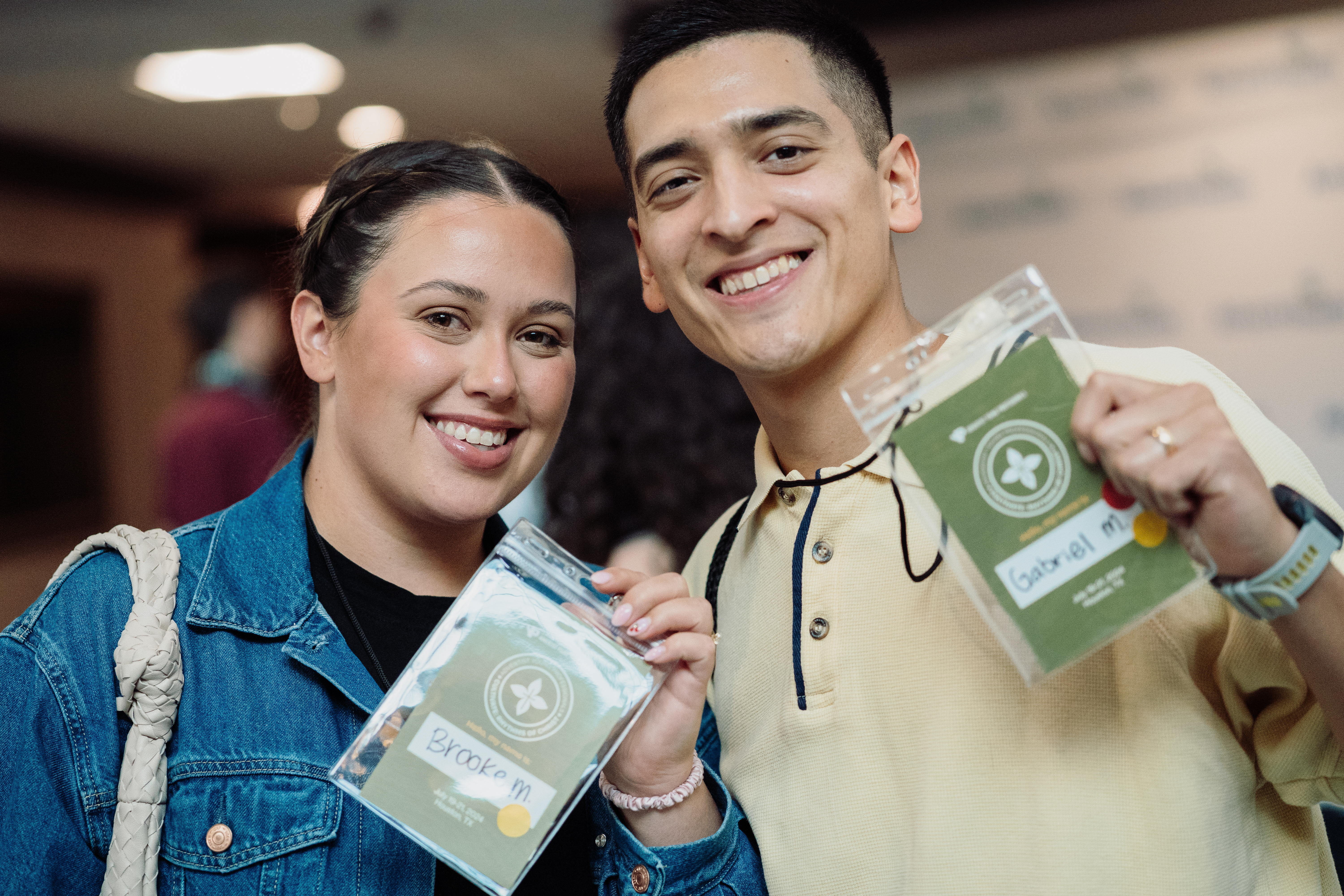 Photo by Sebastian Suarez, couple of young adults pose with their event badges, a male and female attendee in July 2024