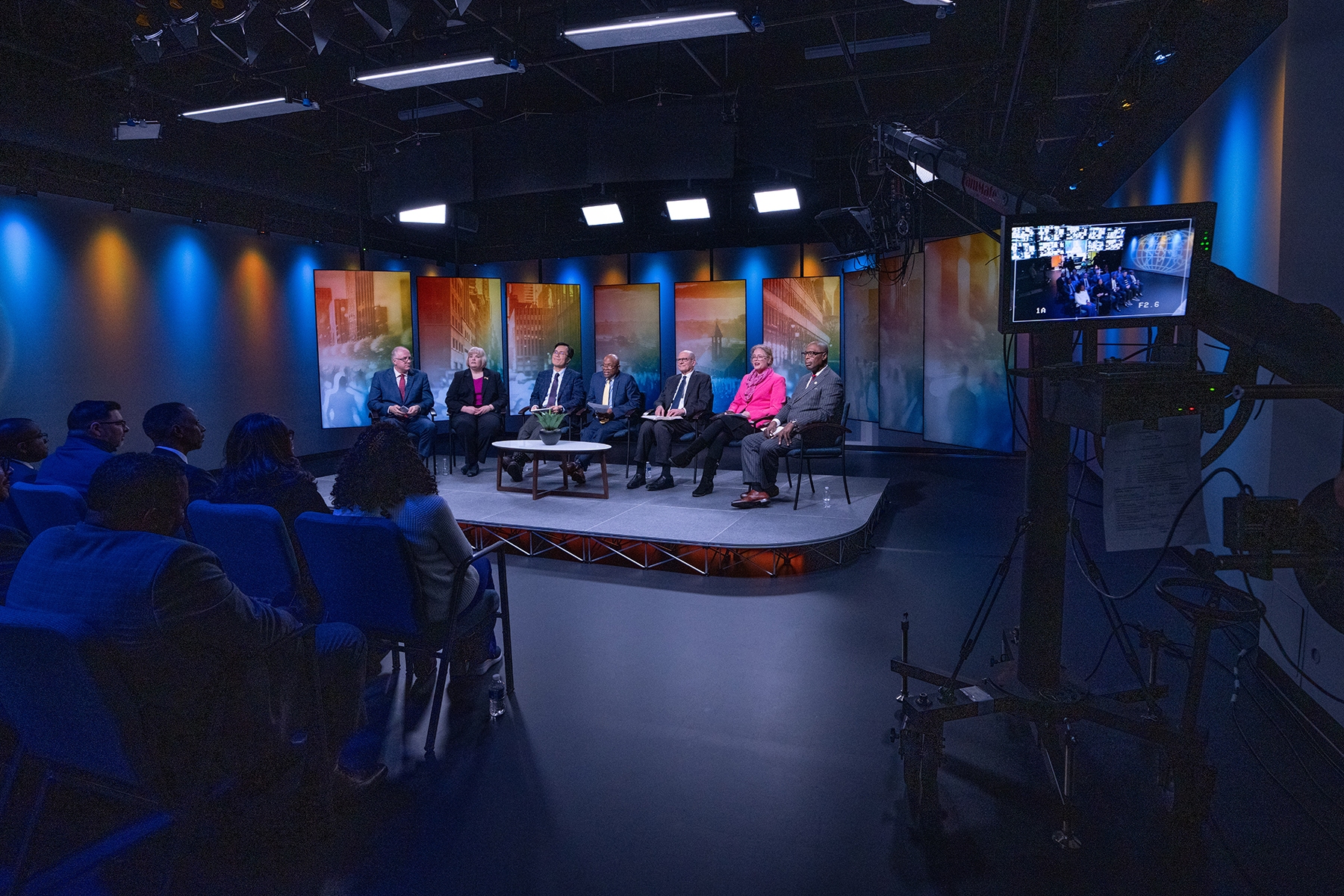 A shot of a panel on a studio stage in front of an audience. 