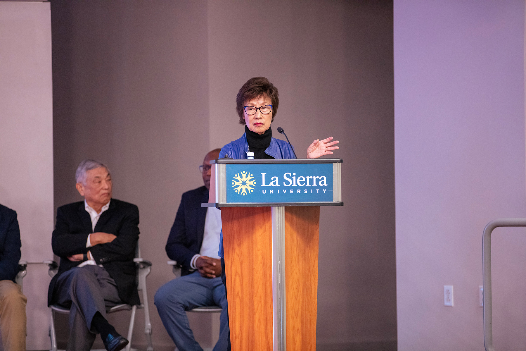 An Asian woman speaks behind a podium