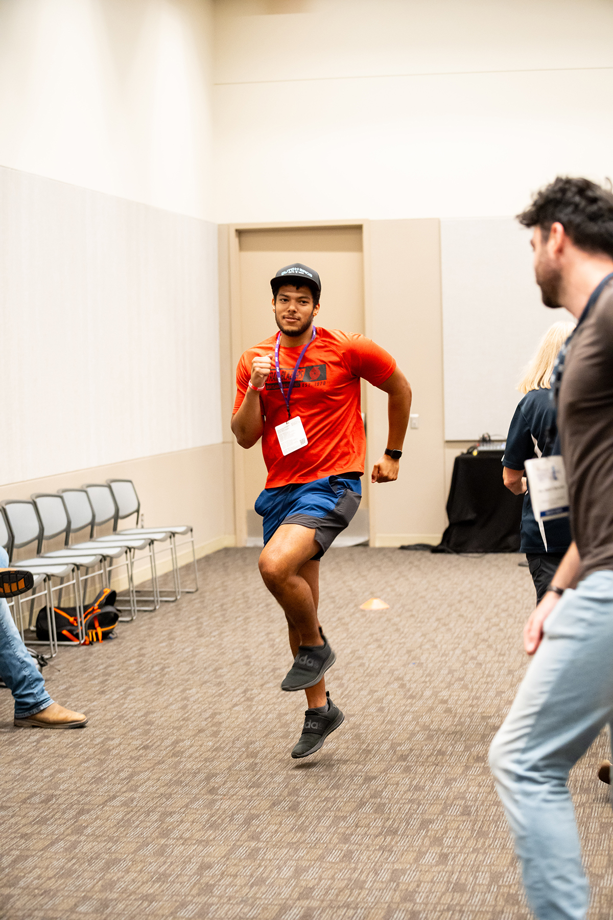 A young man is seen running in spot while another man watches during a class.