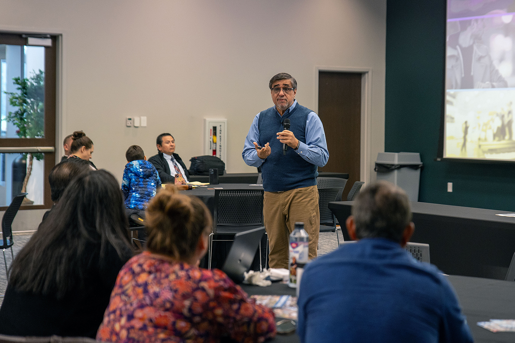 A Hispanic man speaks in front of a small crowd