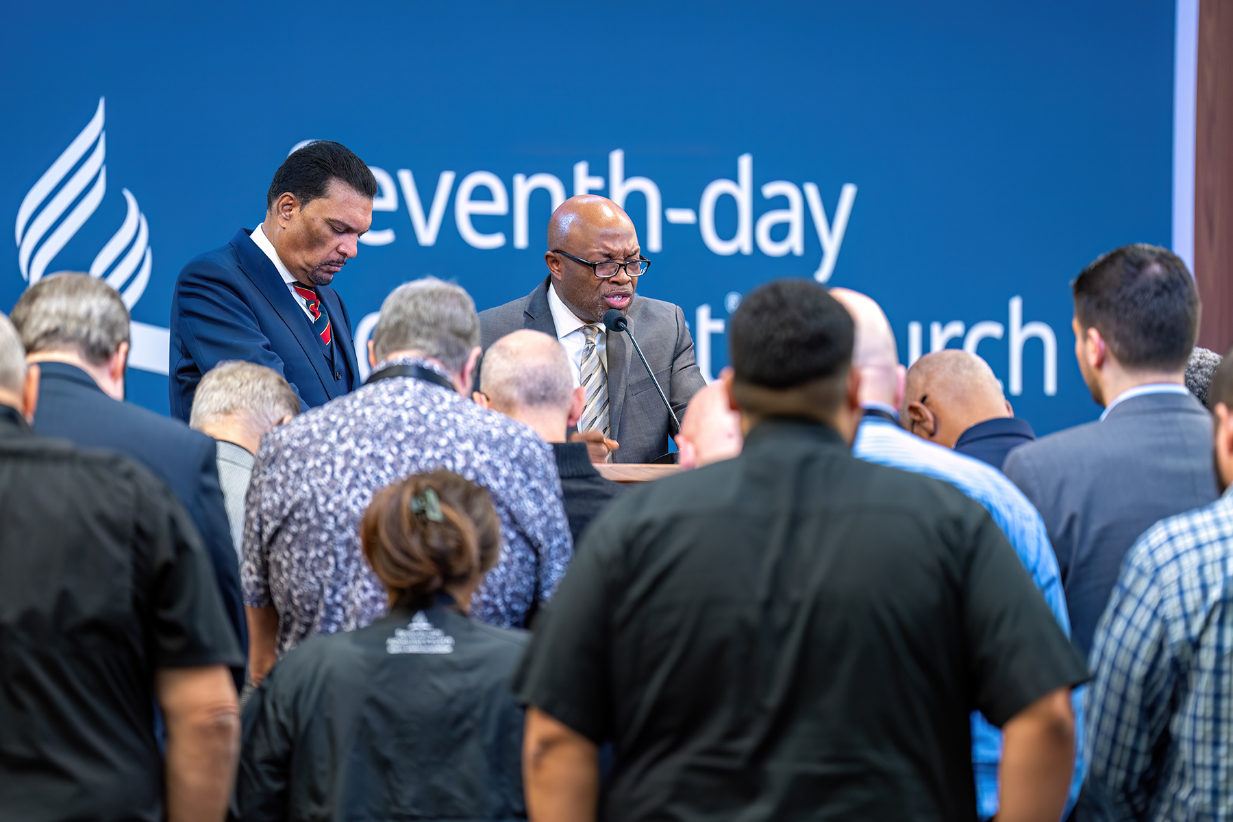 PHOTO 2: Meaningful worship moments, including an altar call by Atlantic Union Conference president Abraham Jules during his morning devotional, set the stage for the treasurer’s report on Monday, November 4, at the NADYEM. Pictured are NAD president G. Alexander Bryant, who is praying, along with Jules (to his left) and several NAD executive committee members and staff. Photo: Art Brondo | North American Division