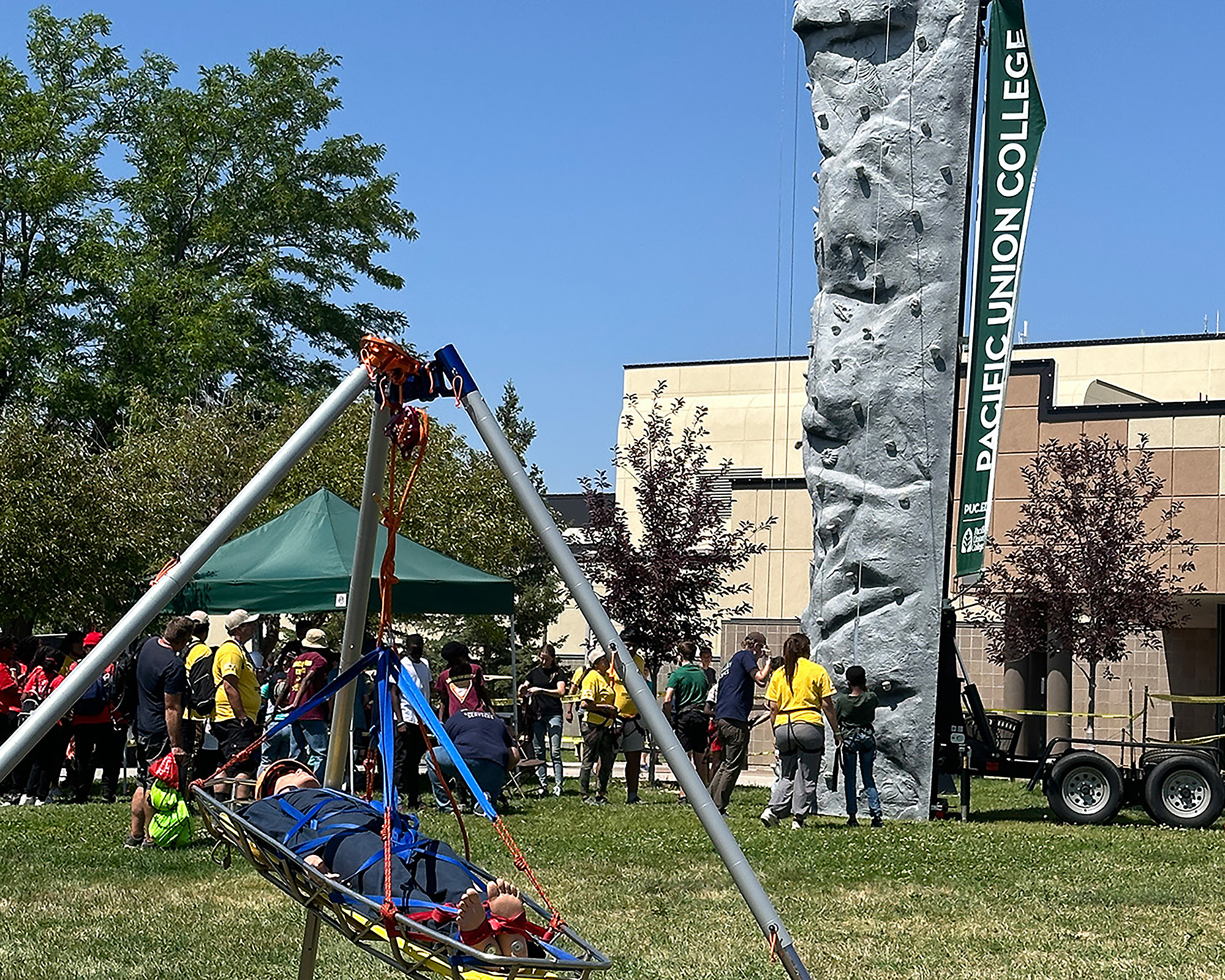 Photo of a dummy on a stretcher and several young people lined up behind a climbing wall