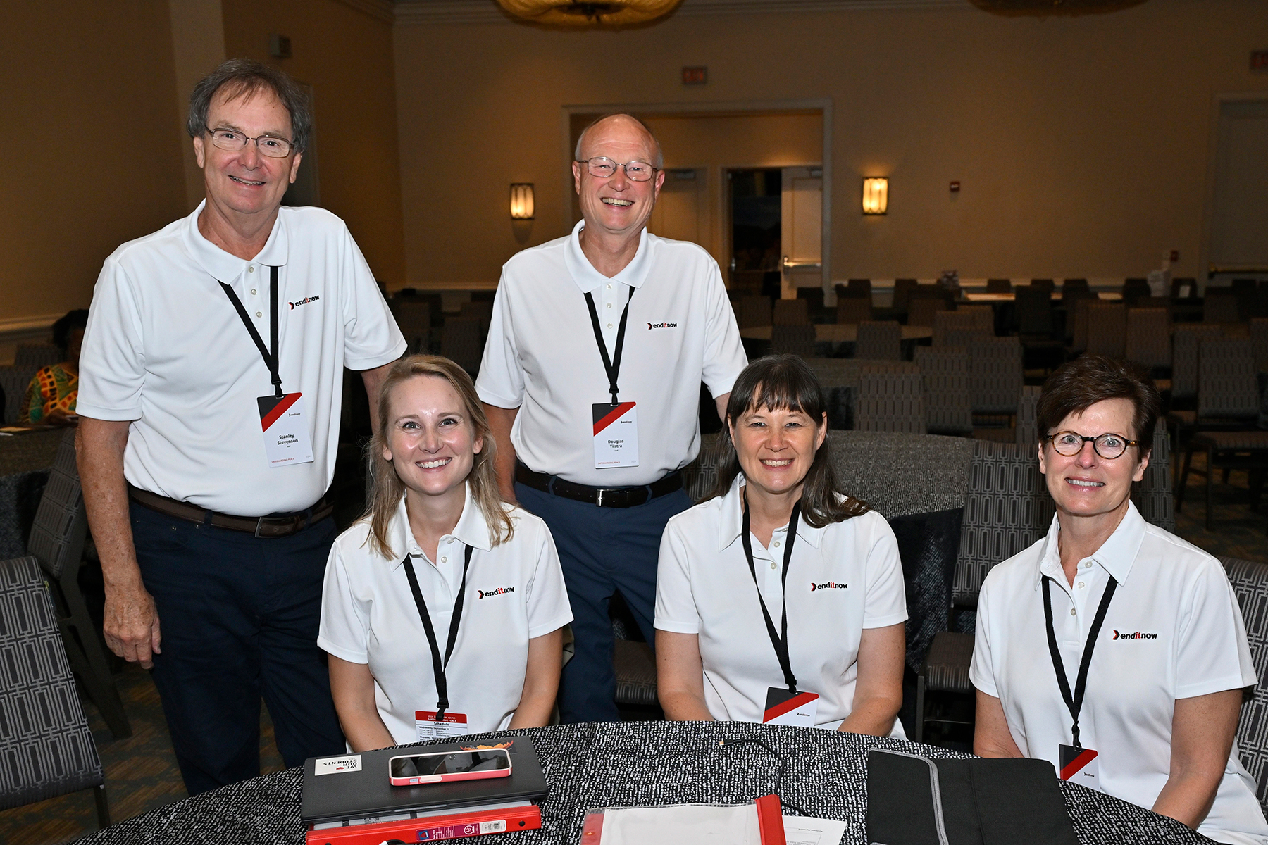 A group of men and women wearing white enditnow shirts.